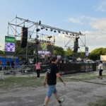 “Fiesta de la Cerveza en Berisso con gran concurrencia, stands cerveceros, escenario en vivo y ambiente familiar al atardecer.”