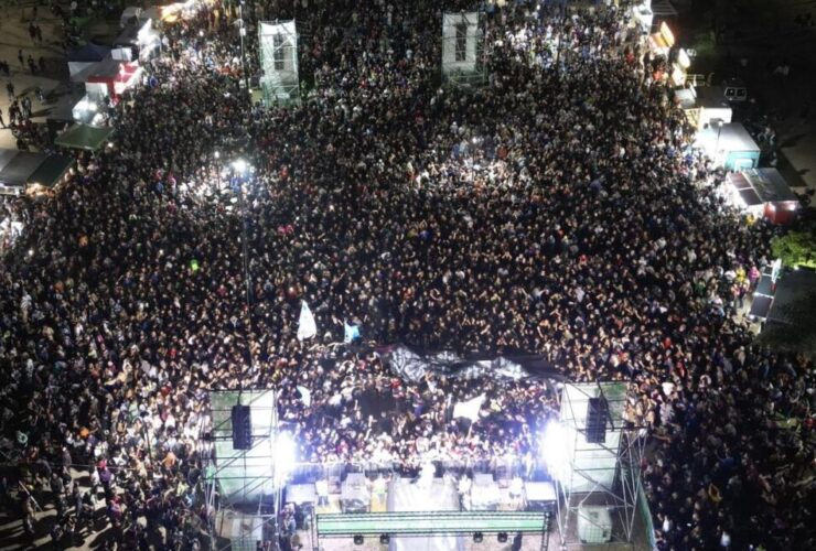 Multitud de personas disfrutando del show en vivo de la banda Tarea Fina en la costa de Punta Lara durante un recital al aire libre.