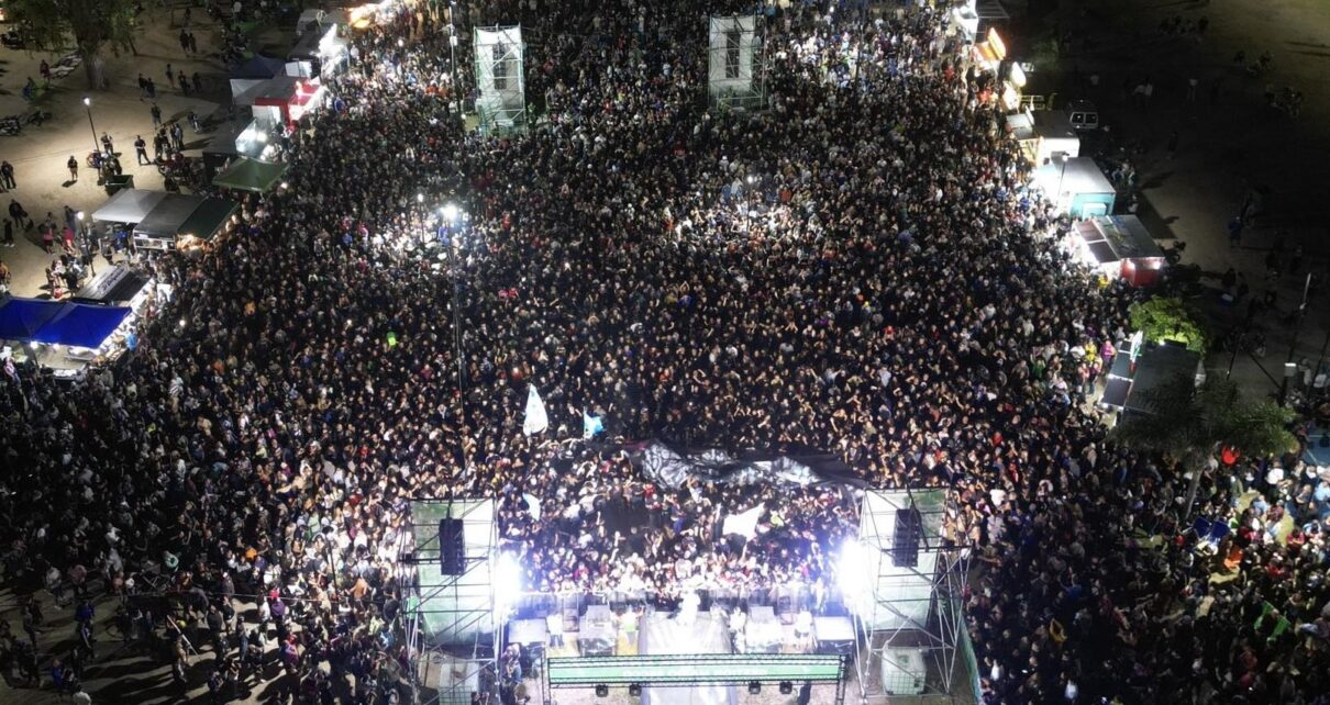 Multitud de personas disfrutando del show en vivo de la banda Tarea Fina en la costa de Punta Lara durante un recital al aire libre.