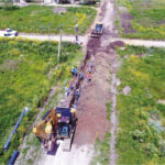 Trabajos de rehabilitación del Acueducto Norte en La Plata con maquinaria y operarios sobre la traza de la cañería principal.