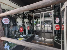 Vidriera de local de ropa en el centro de La Plata con cartel de liquidación por cierre y descuentos del 50%.
