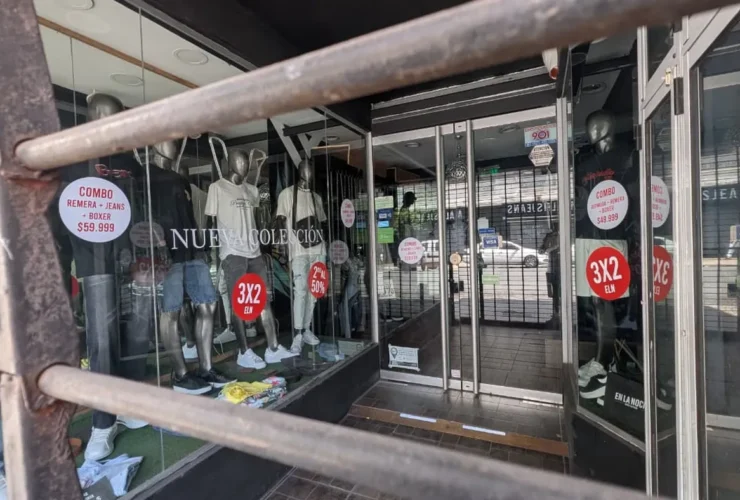 Vidriera de local de ropa en el centro de La Plata con cartel de liquidación por cierre y descuentos del 50%.