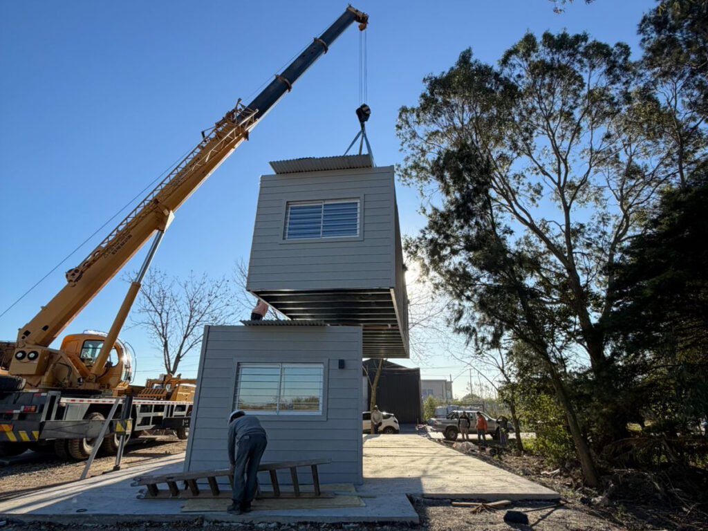 Instalación de la primera vivienda modular sobre avenida Mitre en Berisso durante el avance de un proyecto habitacional sustentable impulsado por el Municipio y la Provincia.